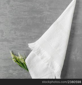 soft towel with a flower in a grey decorative stucco background. top view, isolated. a towel on gray background