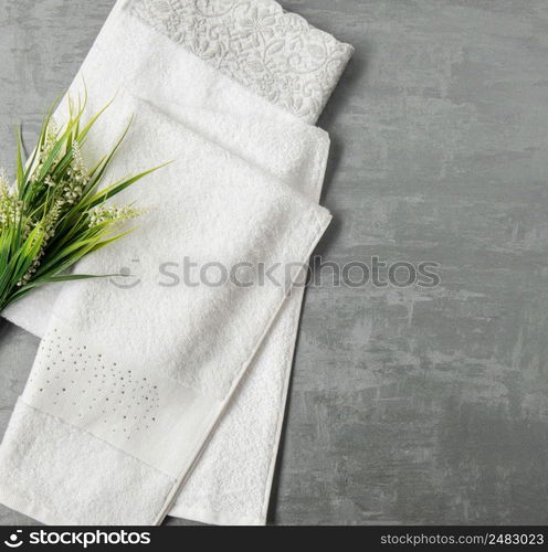 soft towel with a flower in a grey  decorative stucco background. top view, isolated. a towel on gray background