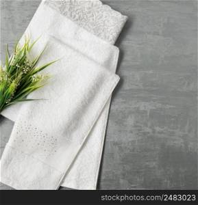 soft towel with a flower in a grey  decorative stucco background. top view, isolated. a towel on gray background