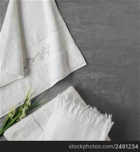 soft towel with a flower in a grey decorative stucco background. top view, isolated. a towel on gray background
