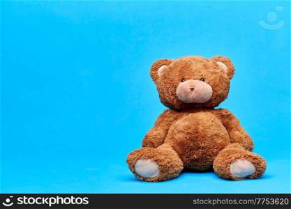 soft toys and childhood concept - brown teddy bear over blue background. brown teddy bear toy over blue background
