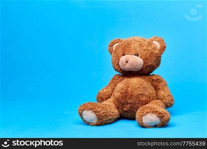 soft toys and childhood concept - brown teddy bear over blue background. brown teddy bear toy over blue background