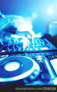 Soft view of man hand disc jockey mixing and blending music tracks on his deck in the darkness of a party or night club.Copy space for text.
