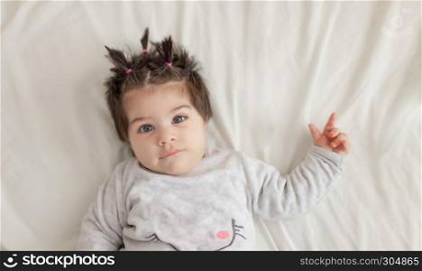 Soft view of Portrait view of cute baby girl lying on bed.Isolated portrait.. Portrait view of cute baby girl lying on bed