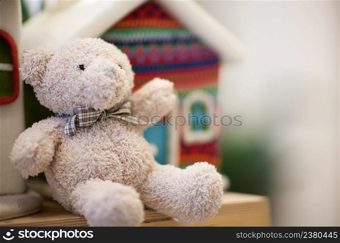 soft white teddy bear on the shelf in the background a small house. soft Christmas toys and decorations