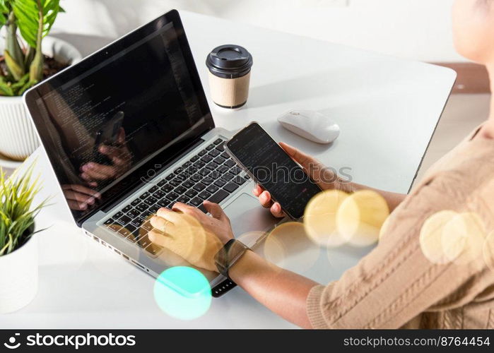 Software developer hands typing data coding programming javascript with laptop computer and mobile phone, Programmer woman looking smartphone program code at workplace, IT startup concept
