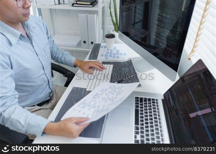 Software development concept, Male programmer read data on document while programming on computer.