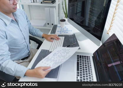 Software development concept, Male programmer read data on document while programming on computer.