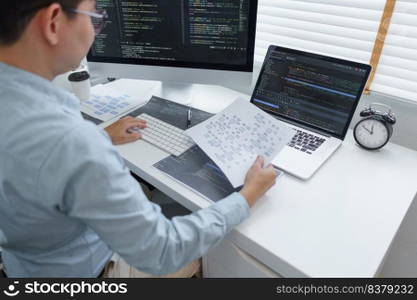 Software development concept, Male programmer read data on document while programming on computer.