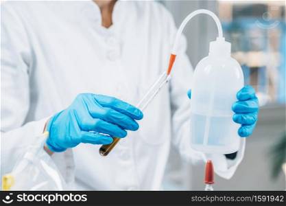 Soil Testing. Female biologist in white coat pouring water into test tube with dissolved samples of soil in laboratory. Agrochemical examination of soil.