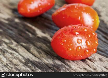 Solanum lycopersicum tomatoes on wooden background