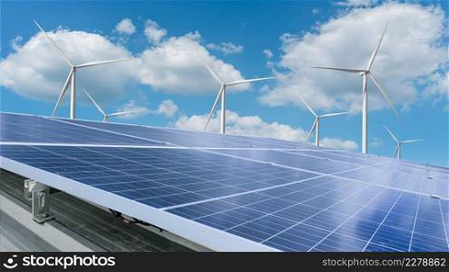 Solar module panels with wind turbine against blue sky background. Environmental energy resources concept.