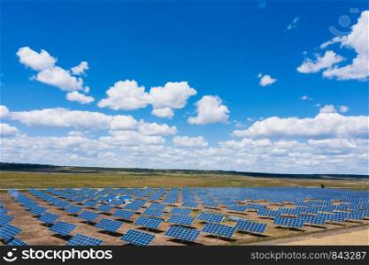 solar panels at the field with the beautiful clouds at sunny summer day aerial view