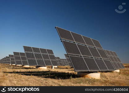 Solar panels in a greenfield, over blue sky