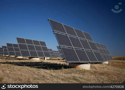 Solar panels in a greenfield, over blue sky