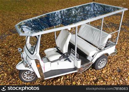 Solar panels on the roof of a tuc tuc, parked on the autumn leafs in a park