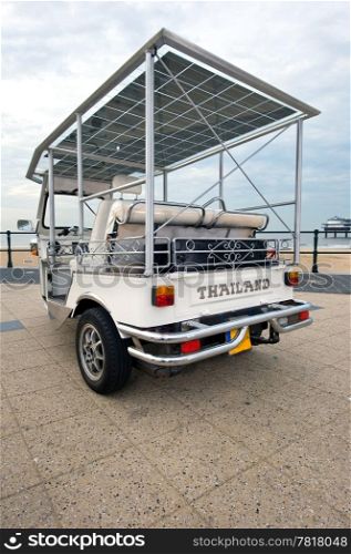 Solar powered tuc tuc on a beach boulevard