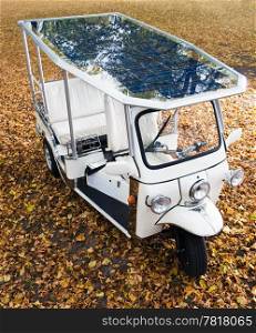 Solar powered tuc tuch parked on an autumn leaf coverd spot in a park