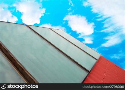 Solar system on the red house roof with blue sunny sky and clouds.