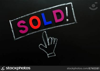 Sold button with a cursor hand drawn in chalk on a blackboard