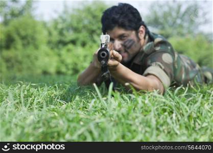 Soldier aiming with rifle while lying on grass