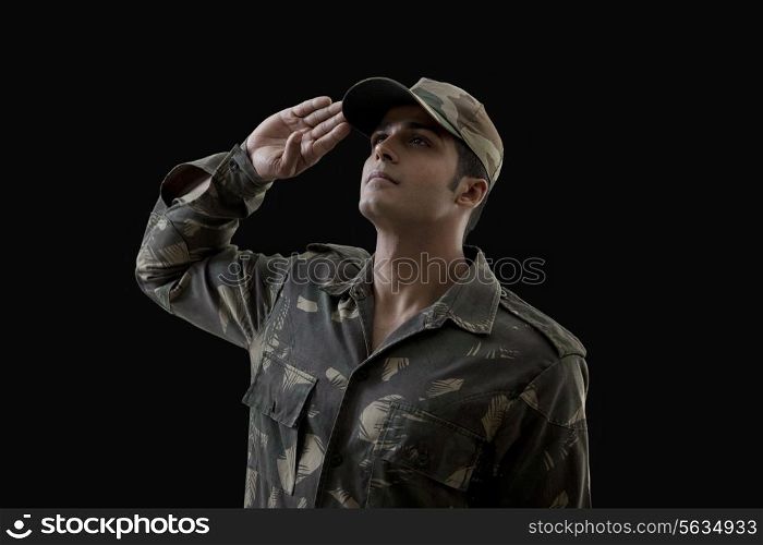 Soldier saluting while looking up against black background