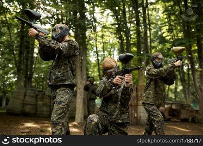 Soldiers in camouflage and masks playing paintball in forest. Extreme sport with pneumatic weapon and paint bullets or markers, military team game outdoors, combat tactics. Soldiers in camouflage and masks playing paintball