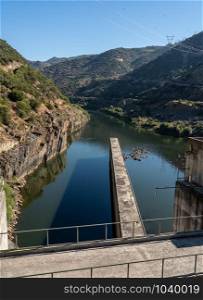 Solid structure of the Valeira dam on River Douro in Portugal looking down into the gorge. Boat rising inside the lock of the Barragem da Valeira dam on the Douro river