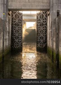 Solid wooden lock gates opening to show the mist from sunrise at the Crestuma Lever dam on River Douro in Portugal. Entering the Crestuma-Lever lock on the Douro river near Porto