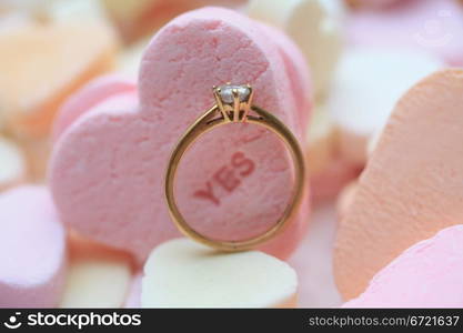 Solitaire diamond engagement ring on valentine candy heart with text yes