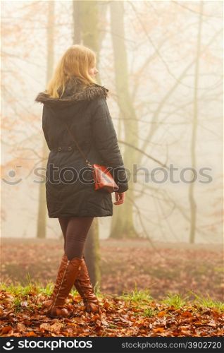 Solitude concept. Sad lonely woman walking relaxing in foggy day in romantic autumn forest park outdoor, back view