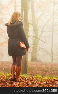 Solitude concept. Sad lonely woman walking relaxing in foggy day in romantic autumn forest park outdoor, back view