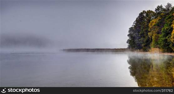 Solitude morning in october. Autumn fog over quiet lake