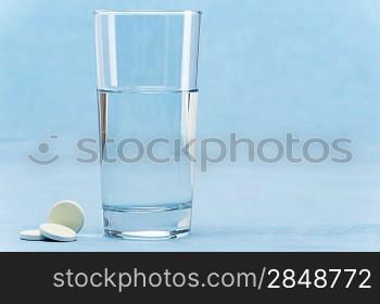 Soluble tablet throw in water glass on blue background