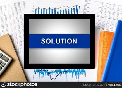 solution word on tablet with financial graph background