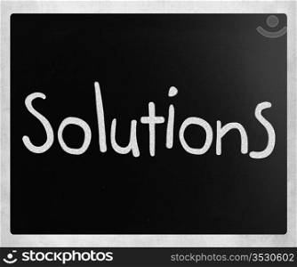 ""Solutions" handwritten with white chalk on a blackboard"