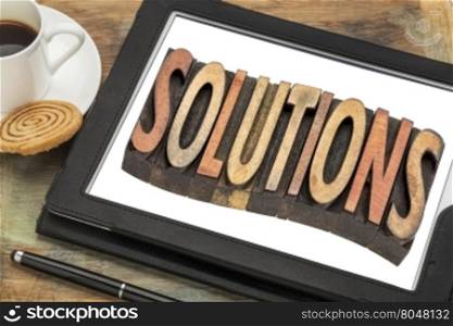 solutions word - text in vintage letterpress wood type printing blocks on a digital tablet with cup of coffee