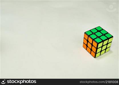 solved rubik&rsquo;s cube in yellow, green and orange on white background with copy space 2.. solved rubik&rsquo;s cube in yellow green and orange on white background with copy space 2