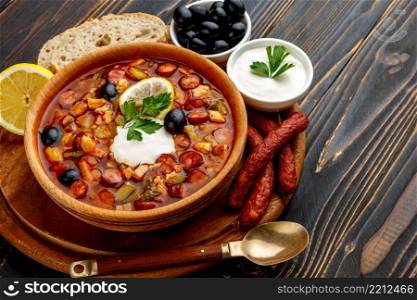Solyanka - Russian traditional meat soup on wooden background. Solyanka - Russian traditional meat soup