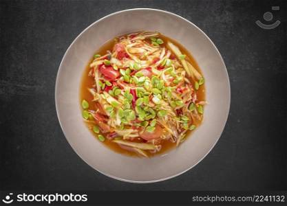 Som Tum, Som Tam, Thai E-San food, spicy papaya salad with pickled fish, tomato, lime and chilli topping with phatakin seed on dark tone texture background, top view