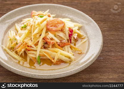 Som Tum Thai, Som Tam Thai, Thai food, spicy papaya salad with, tomato, lime and chilli topping with dried shrimp on natural wood texture background, top view