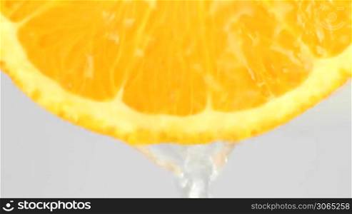 some cut orange with water flowing over the fruity part, eine aufgeschnittene Orange uber die Wasser flie?t und nach unten tropft