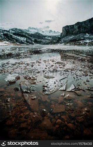 Some frozen water and pieces of ice in a frozen lake in the middle of the mountains during winter