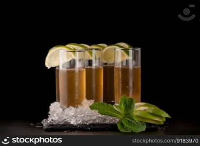 some glasses with yellow citron drink and ice on a black stone on a dark background. beverages on a dark background