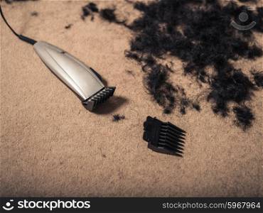 Some hair clippers on the floor with piles of hair around them