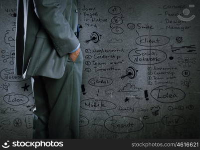 Some ideas for success. Bottom view of businessman and sketches of ideas on wall