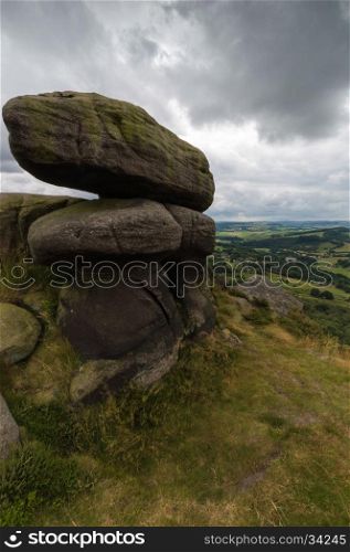 Some large bolders in the foreground on top of a hill near Froggatt Edge in the Peak District, Derbyshire, UK