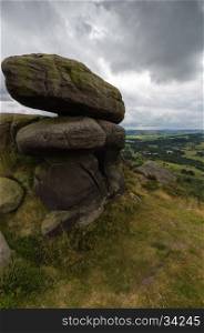 Some large bolders in the foreground on top of a hill near Froggatt Edge in the Peak District, Derbyshire, UK