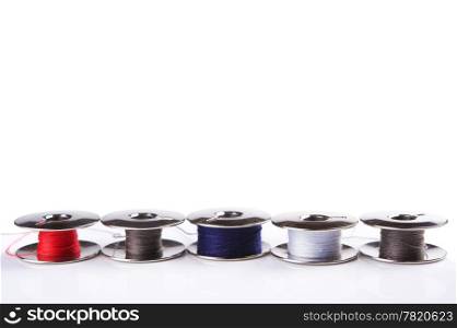 Some metal spools with multicoloured threads isolated on white