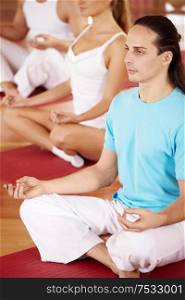 Some persons sit in a lotus pose in sports club